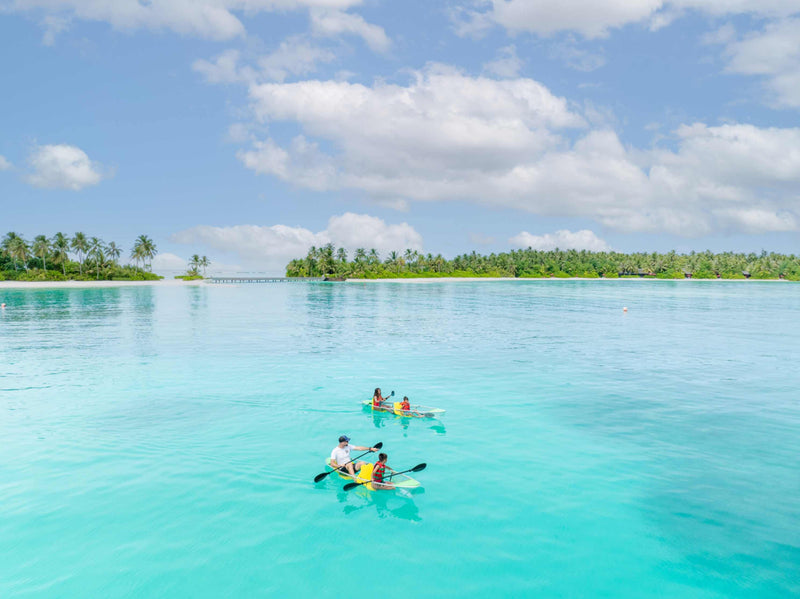Guests paddleboarding and kayaking in the shallow lagoon at Niyama Private Islands