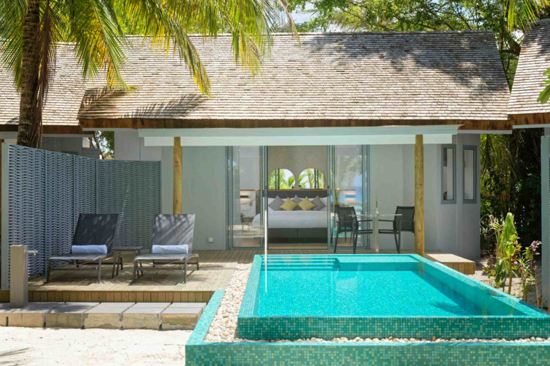 Beach villa with a turquoise private pool, sun loungers and palms overhead
