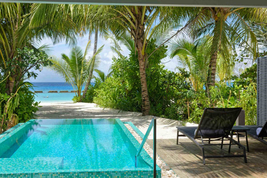 Long private pool set among palms at Maafushivaru, with a sand path through to the beach