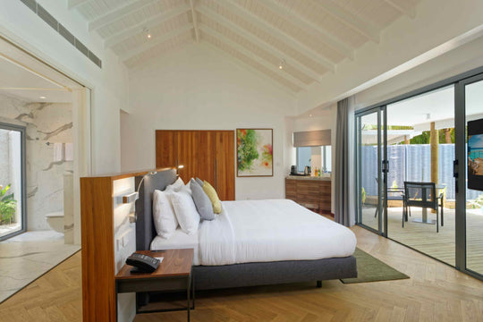 Beach villa bedroom with timber floors, an open bathroom and glass doors to the garden
