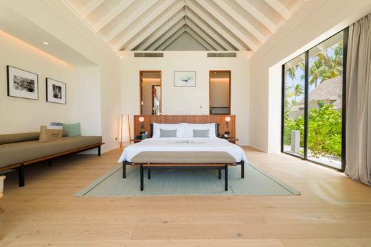 A Beach Pool Villa bedroom at ananea Madivaru Maldives with a daybed along the wall and the garden through the glass