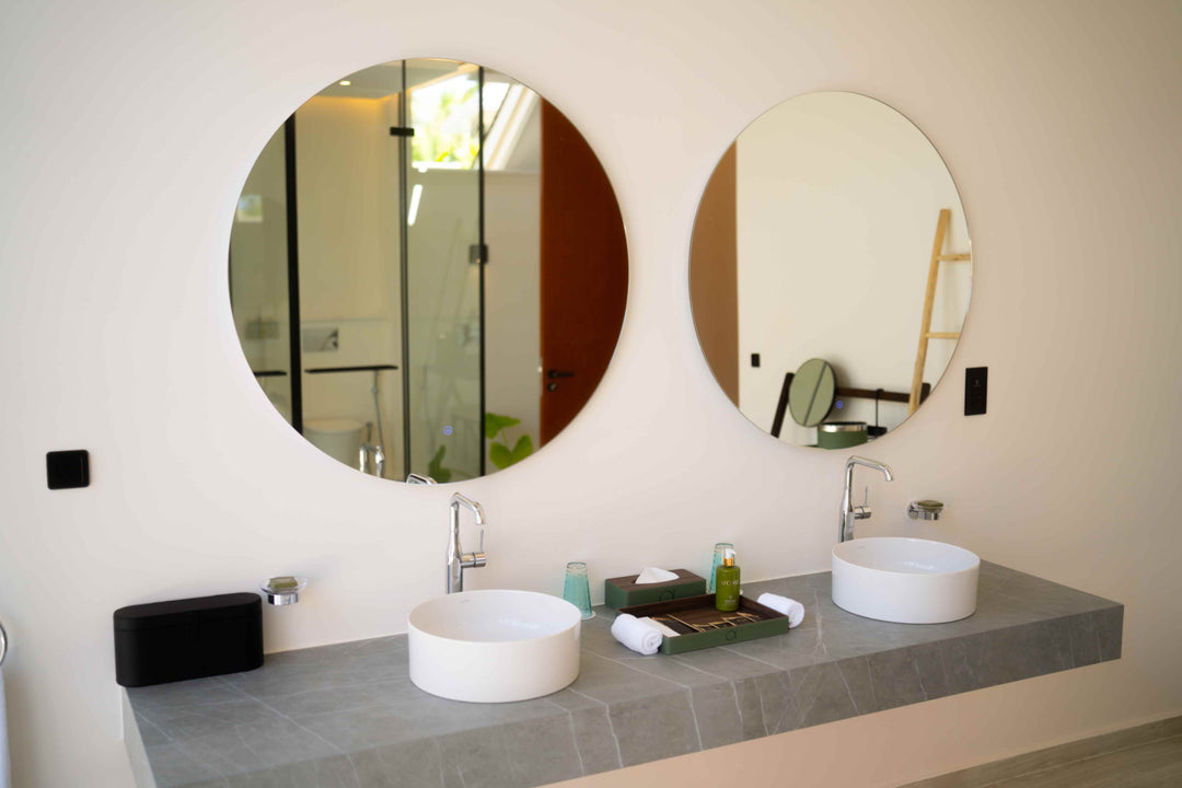 Twin round mirrors above the basins in a villa bathroom at ananea Madivaru Maldives