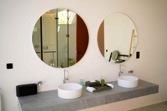 Twin round mirrors above the basins in a villa bathroom at ananea Madivaru Maldives