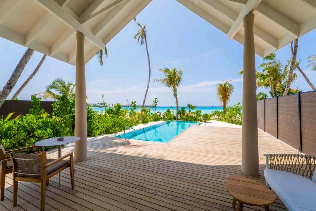 The pool of a beach villa at ananea Madivaru Maldives, the sea visible past the palms beyond the wall