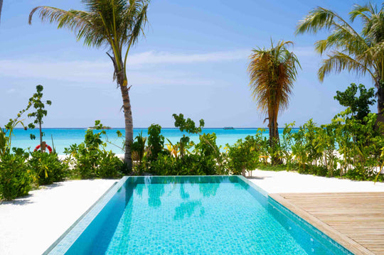 A beach villa pool at ananea Madivaru Maldives with the lagoon and a distant boat beyond the palms