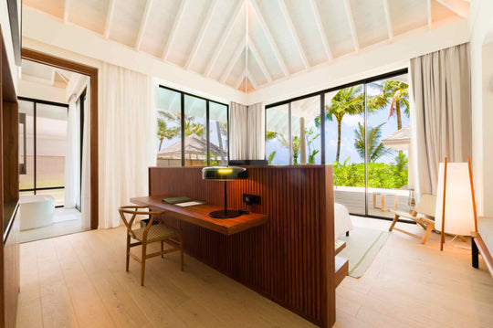 The sitting area of a Deluxe Beach Pool Villa at ananea Madivaru Maldives, a writing desk against floor to ceiling glass