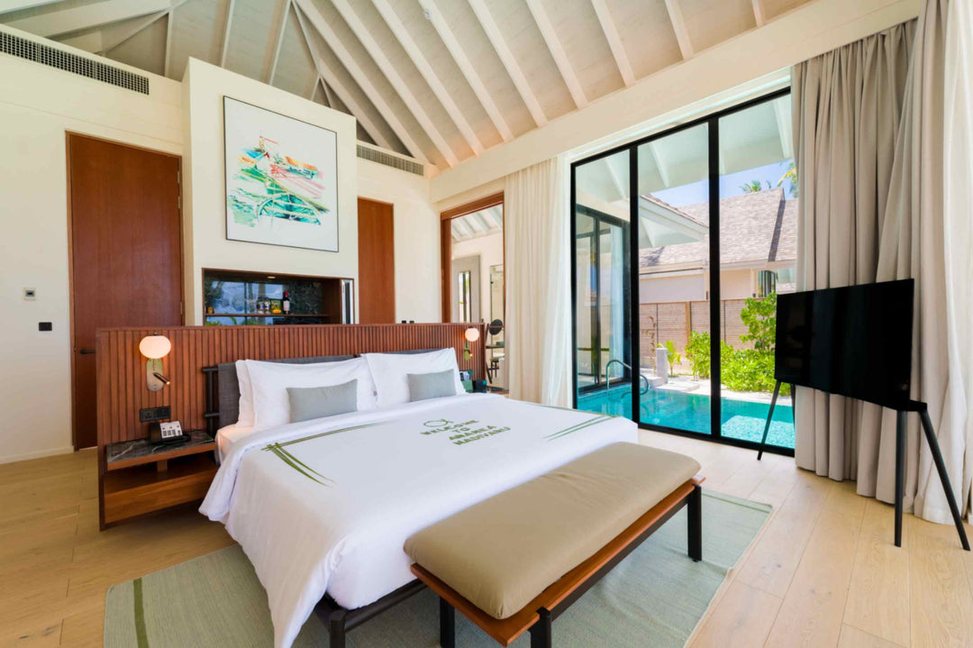 A Deluxe Beach Pool Villa bedroom at ananea Madivaru Maldives, the private pool visible through the glass beside the bed