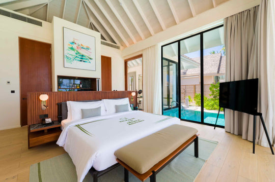 A Deluxe Beach Pool Villa bedroom at ananea Madivaru Maldives, the private pool visible through the glass beside the bed