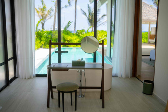 A villa bathroom at ananea Madivaru Maldives, round mirror above the basin with the pool through the window