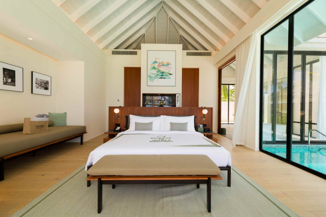 A Deluxe Beach Pool Villa bedroom at ananea Madivaru Maldives, daybed along one wall and the pool through the glass