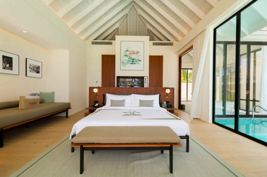 A Deluxe Beach Pool Villa bedroom at ananea Madivaru Maldives, daybed along one wall and the pool through the glass