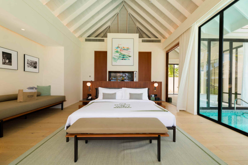 A Deluxe Beach Pool Villa bedroom at ananea Madivaru Maldives, daybed along one wall and the pool through the glass