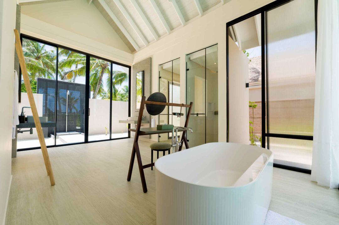 A villa bathroom at ananea Madivaru Maldives looking out through glass to the garden