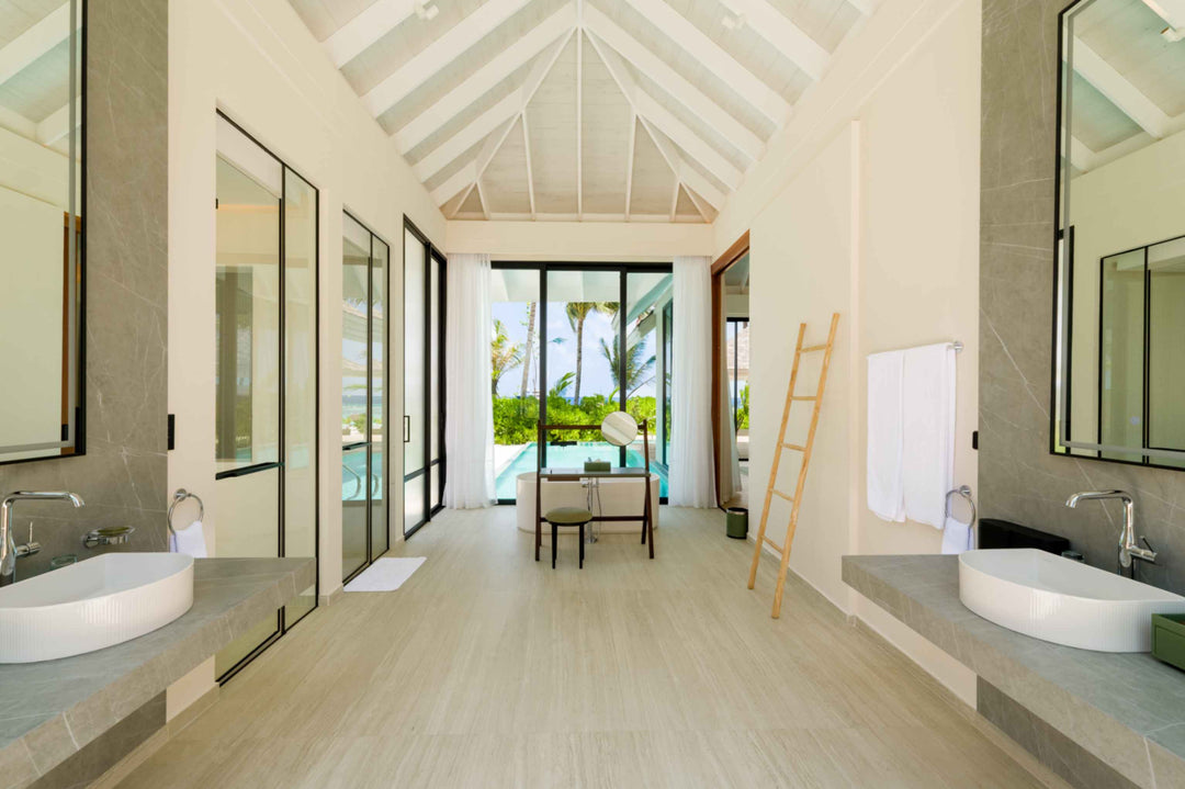 A villa bathroom at ananea Madivaru Maldives with twin basins facing each other and the garden beyond