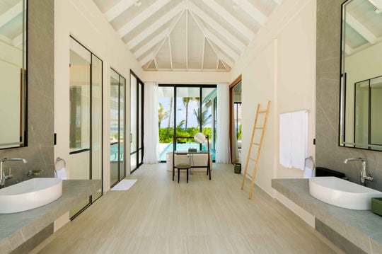 A villa bathroom at ananea Madivaru Maldives with twin basins facing each other and the garden beyond