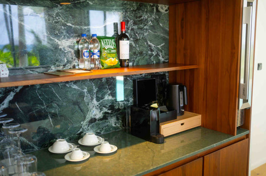 The minibar in a villa at ananea Madivaru Maldives, bottles on a marble counter with a coffee machine below