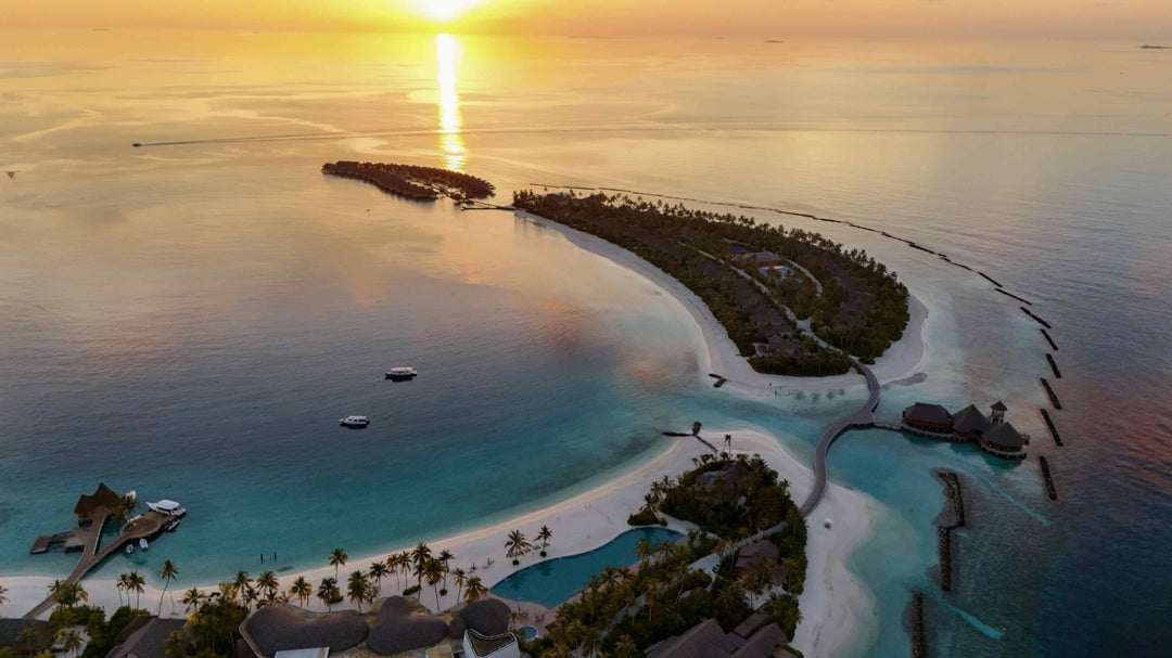 ananea Madivaru Maldives from the air at sunset, the island and its reef against still water