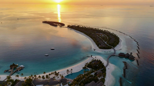 ananea Madivaru Maldives from the air at sunset, the island and its reef against still water