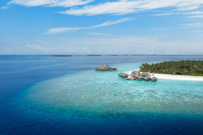 The overwater Anantara Spa at Anantara Kihavah Maldives Villas from the air, standing out over the reef