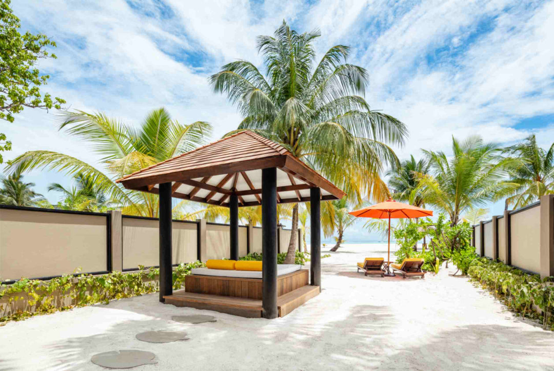 Angsana Velavaru, Dhaalu Atoll — a timber sala with a daybed on the sand, looking out to the sea