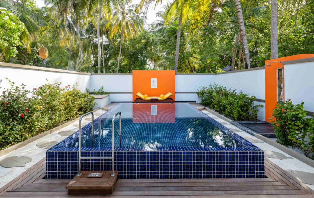 Angsana Velavaru, Dhaalu Atoll — blue-tiled private pool on a timber deck, in a walled garden with an orange panel