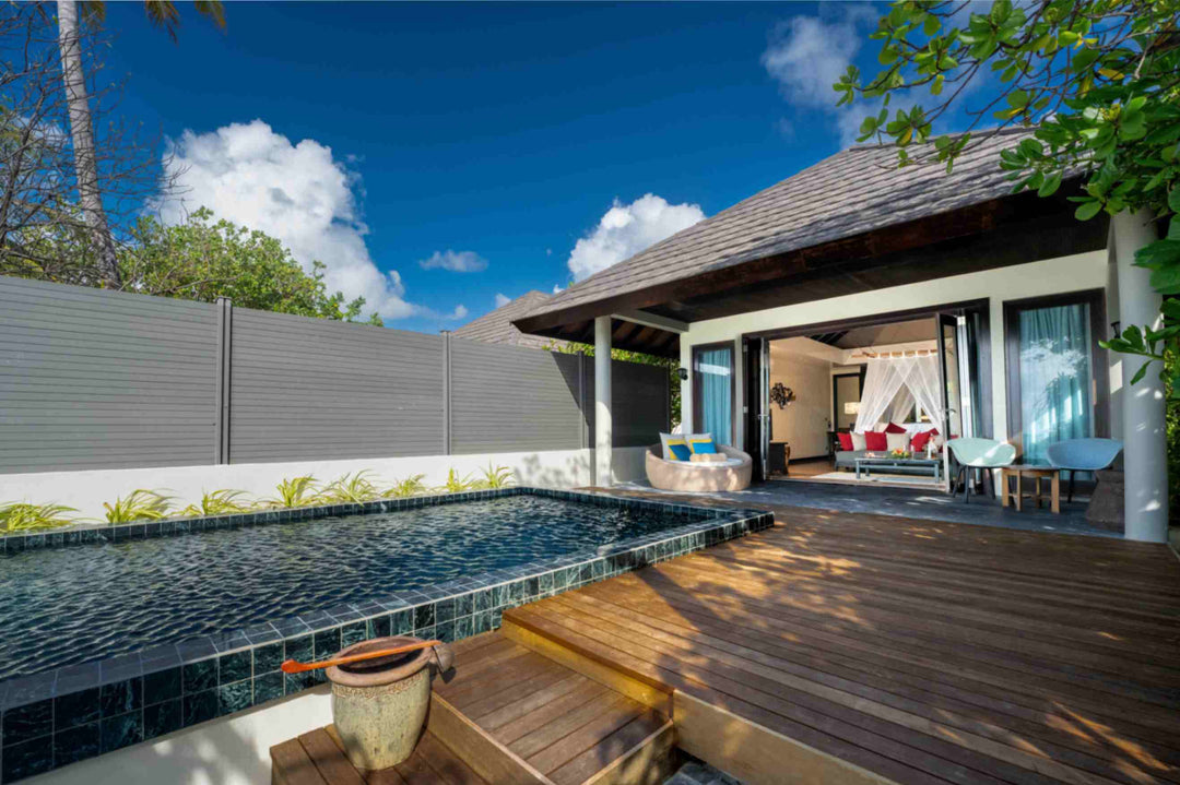 Atmosphere Kanifushi, Lhaviyani Atoll — Kanifushi Beach Villa with Pool in daylight: private pool and timber deck in front of the open villa, white privacy wall along one side.