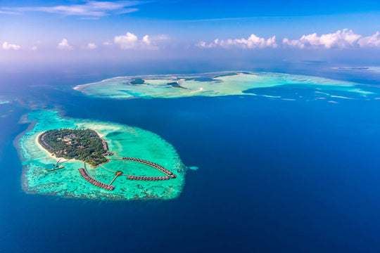 The whole of Ayada Maldives from high above, a small green island inside a wide turquoise lagoon