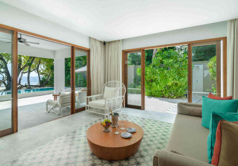 The sitting room of a Beach Pool Villa at Amilla Maldives, opening onto the pool and garden
