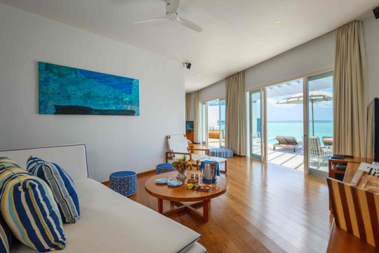 The living room of a Lagoon Pool Villa at Amilla Maldives, blue artwork above a low round table