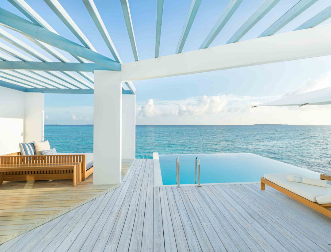 The deck of a Reef Water Pool Villa at Amilla Maldives, pool and loungers under a slatted pergola