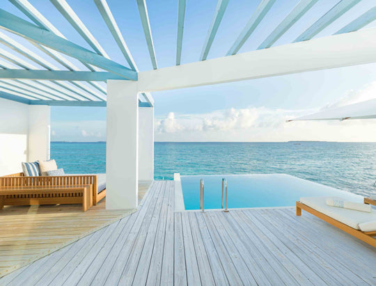 The deck of a Reef Water Pool Villa at Amilla Maldives, pool and loungers under a slatted pergola