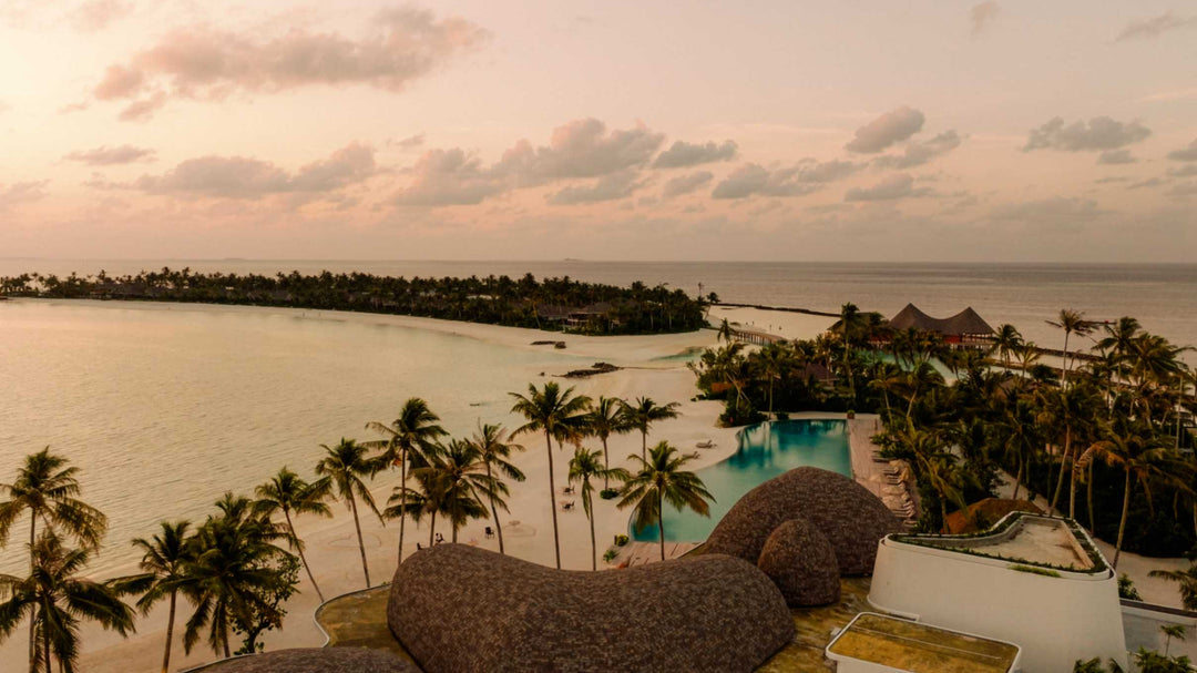 ananea Madivaru Maldives from the air in evening light, the pool and thatched buildings among the palms