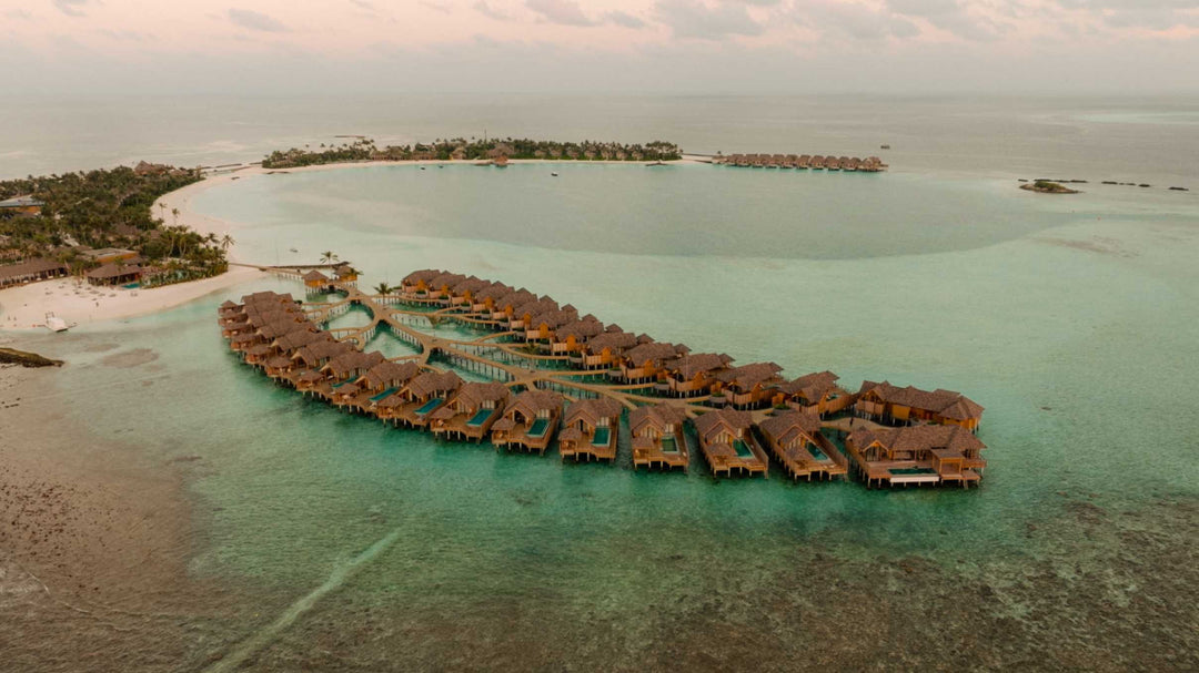 The overwater villas at ananea Madivaru Maldives from the air, curving round the edge of the lagoon