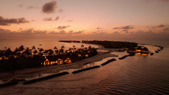 ananea Madivaru Maldives at sunset from the air, lights coming on along the island