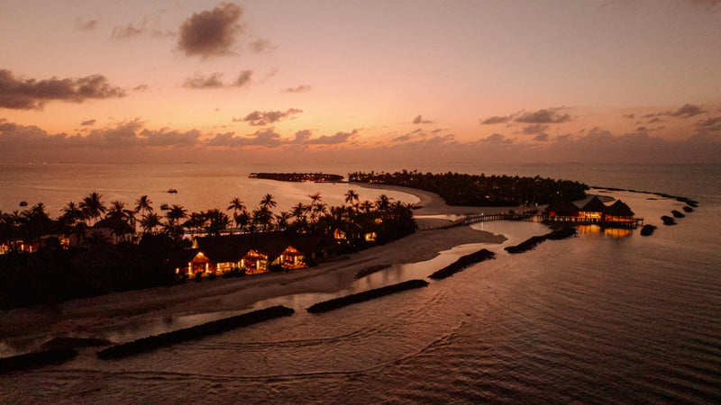 ananea Madivaru Maldives at sunset from the air, lights coming on along the island