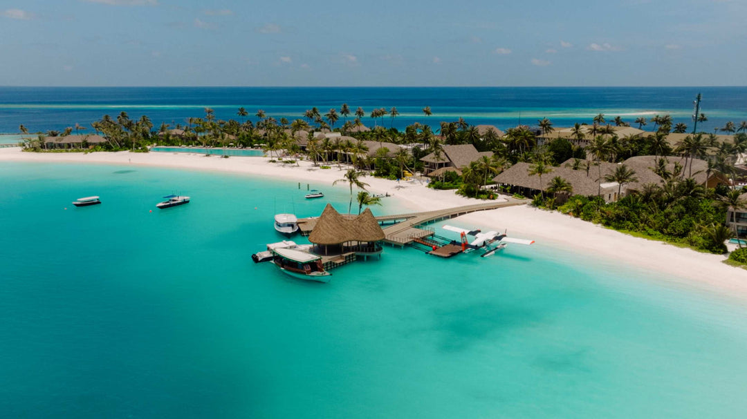 The arrival jetty and overwater pavilion at ananea Madivaru Maldives, boats on the turquoise lagoon