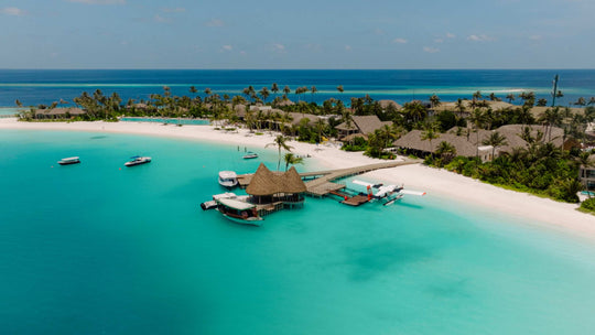 The arrival jetty and overwater pavilion at ananea Madivaru Maldives, boats on the turquoise lagoon