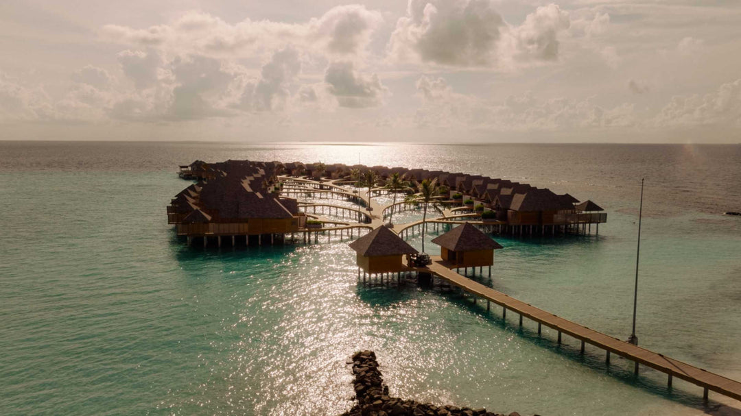 The overwater villas at ananea Madivaru Maldives at dusk, the jetty running out across still water