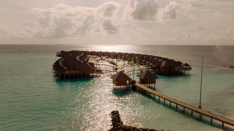 The overwater villas at ananea Madivaru Maldives at dusk, the jetty running out across still water