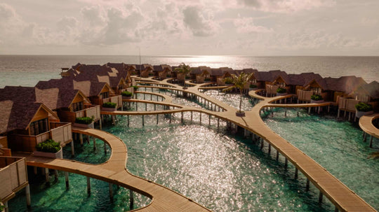 The curving overwater walkway at ananea Madivaru Maldives from the air, villas on both sides of it