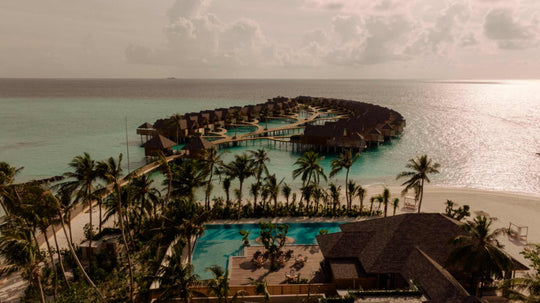 ananea Madivaru Maldives from the air at dusk, the overwater villas reaching out from the palms