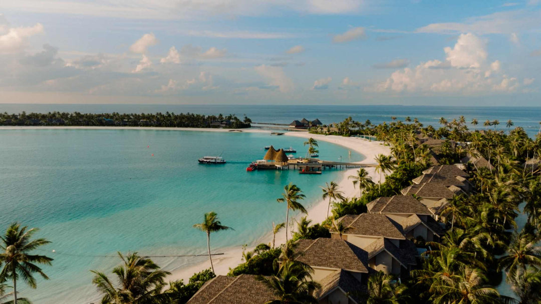 The overwater restaurant and beach at ananea Madivaru Maldives from the air, palms crowding the shoreline