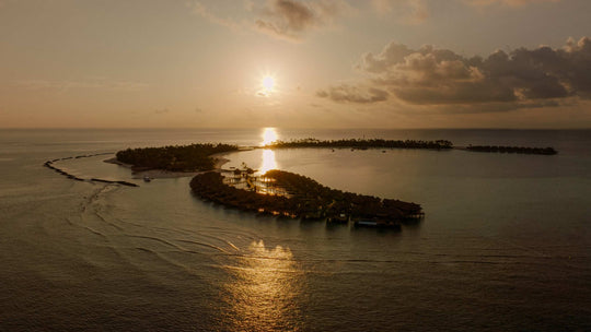 Sunset behind ananea Madivaru Maldives, the island low on the horizon across open water