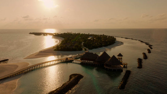 ananea Madivaru Maldives at sunset from the air, the jetty running out to the overwater pavilion