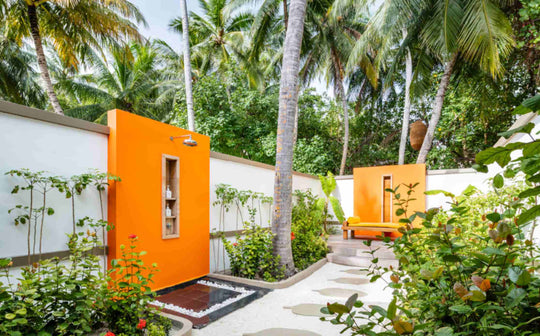Angsana Velavaru, Dhaalu Atoll — walled garden terrace with an outdoor shower behind an orange panel, under palms