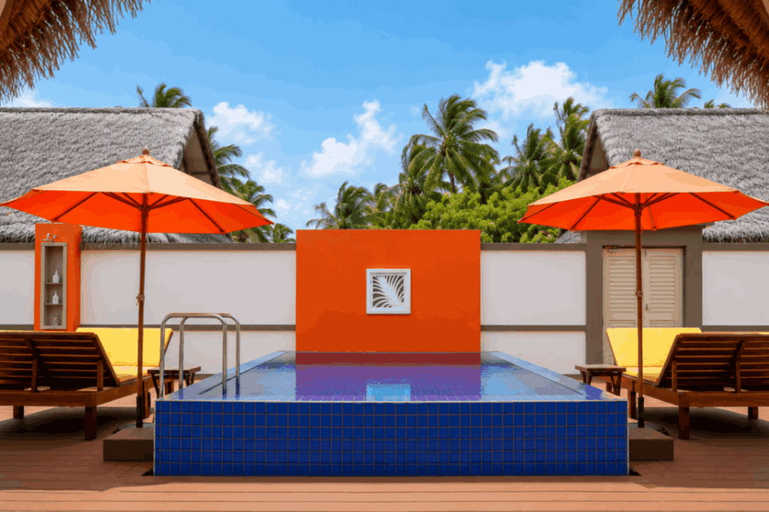Angsana Velavaru, Dhaalu Atoll — the three-bedroom villa pool seen across the deck, with an orange panel between the parasols