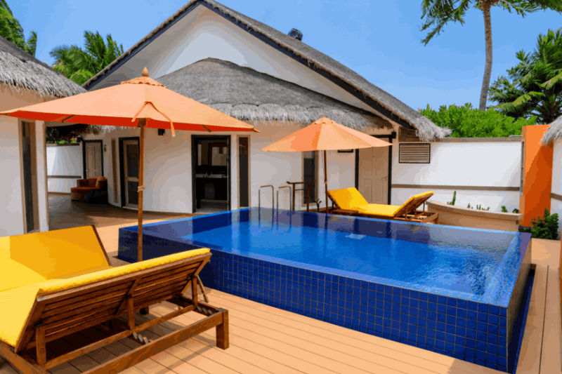 The pool of the three-bedroom villa at Angsana Velavaru, with two orange parasols and loungers along the deck.