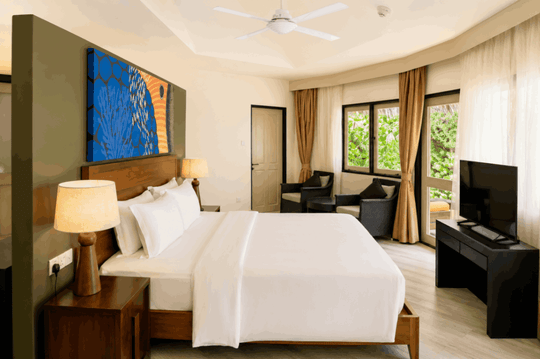 Angsana Velavaru, Dhaalu Atoll — king bedroom in the three-bedroom villa, with blue wall art and armchairs