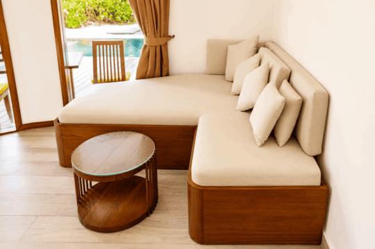 Angsana Velavaru, Dhaalu Atoll — daybed and low table inside a beach villa, with the pool just outside the doors