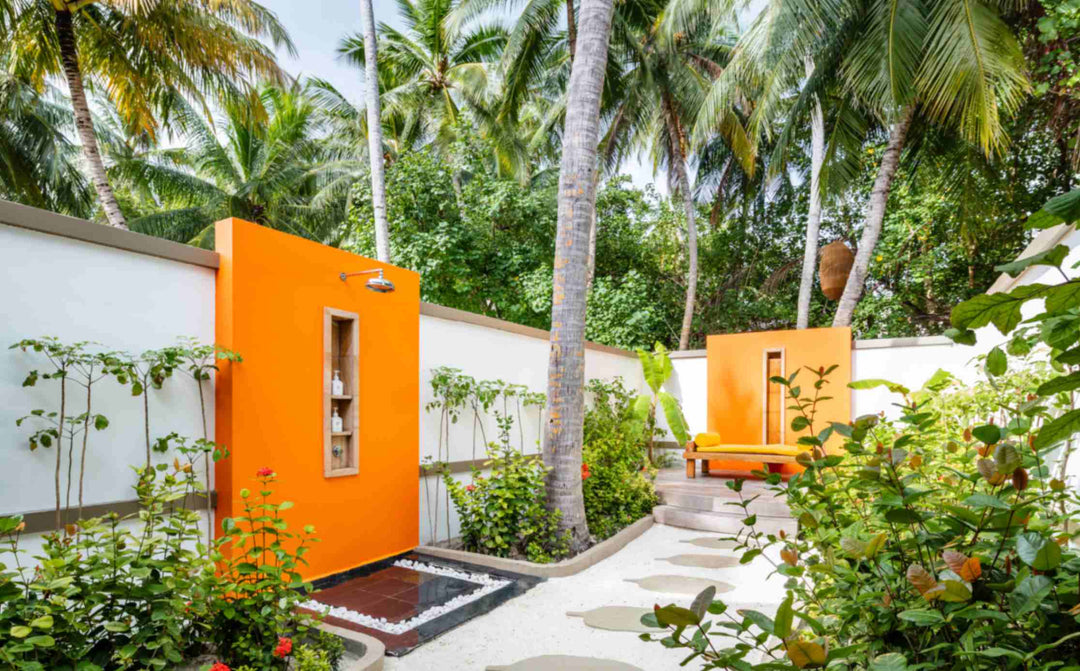 Angsana Velavaru, Dhaalu Atoll — walled garden with an outdoor shower behind an orange panel and a path of stepping stones